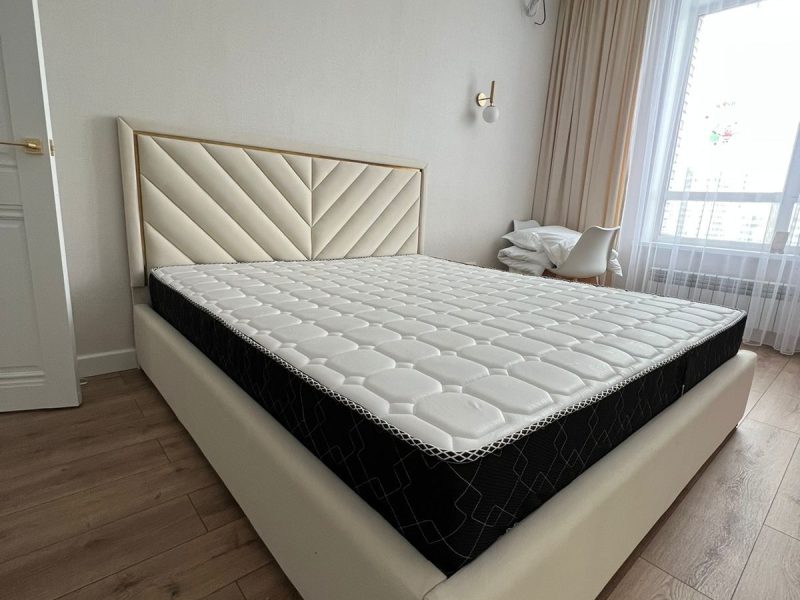 Light upholstered bed with geometric headboard and gold trim – ReNew Studio