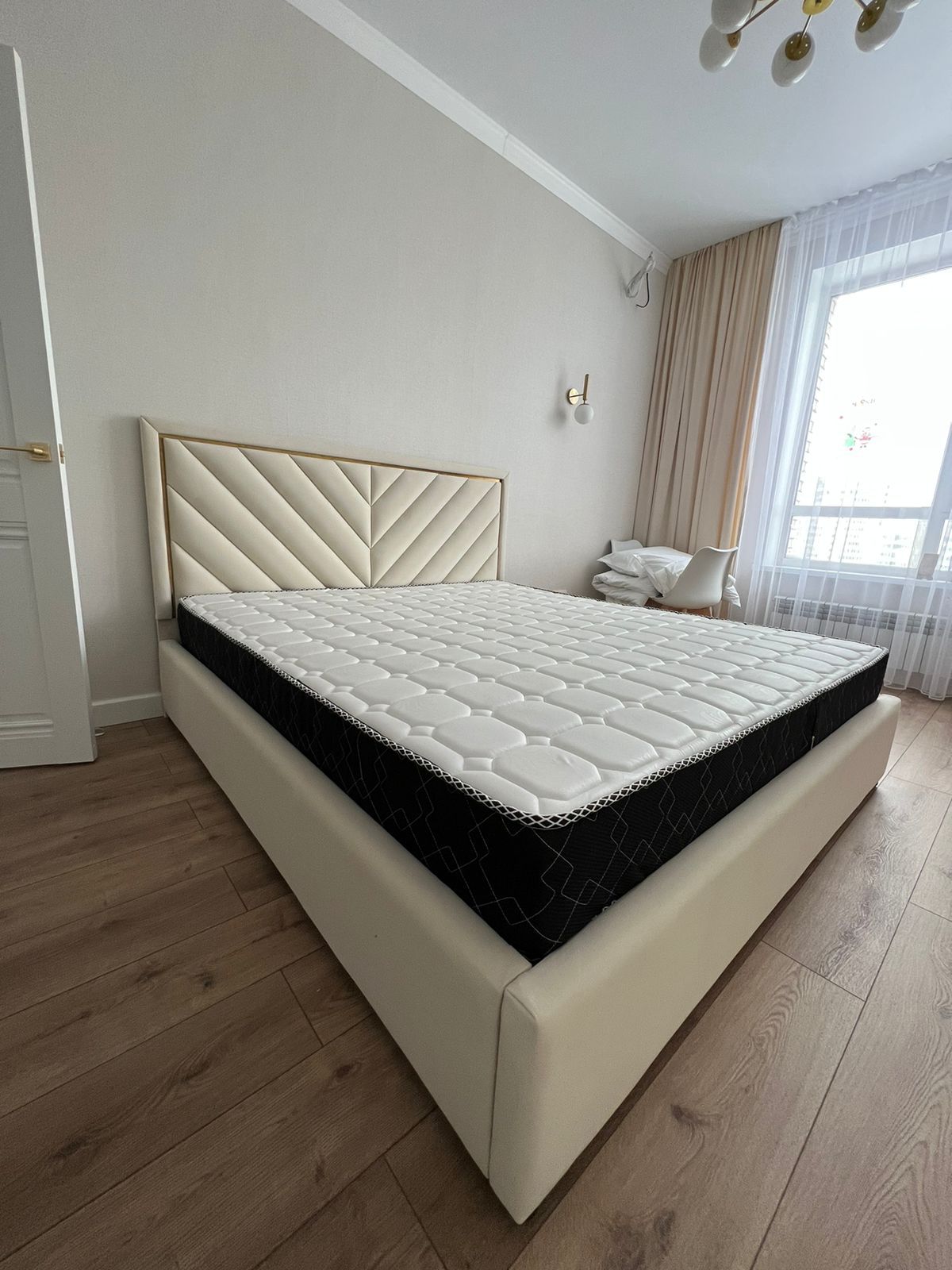 Light upholstered bed with geometric headboard and gold trim – ReNew Studio